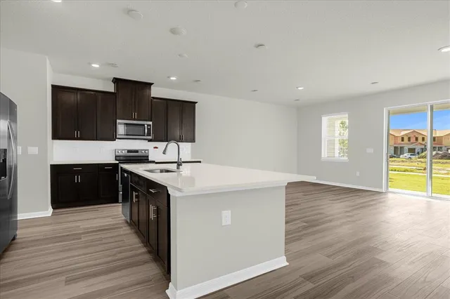 a kitchen with stainless steel appliances kitchen island granite countertop a stove a sink and a refrigerator