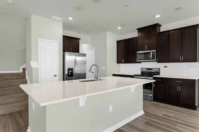 a large kitchen with stainless steel appliances wooden cabinets and a wooden floor