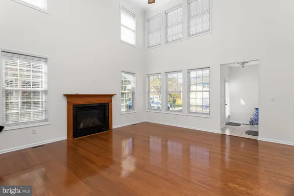 an empty room with wooden floor fireplace and windows