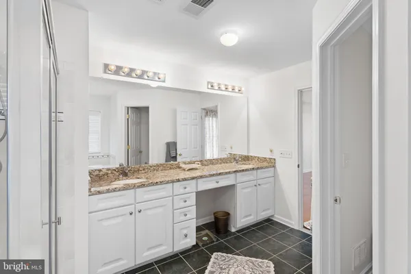 a spacious bathroom with a granite countertop double vanity sink mirror and