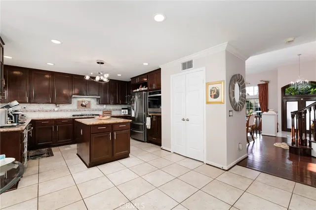 a kitchen with stainless steel appliances kitchen island granite countertop a refrigerator and a sink