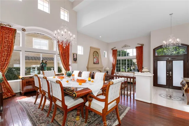 a dining room with wooden floor a chandelier a glass table and chairs