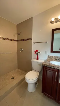 a bathroom with a granite countertop sink a toilet and shower