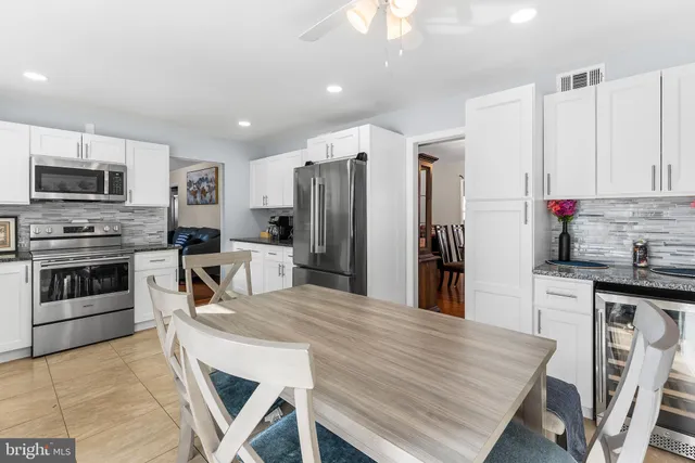 a kitchen with stainless steel appliances granite countertop a stove a refrigerator a kitchen island a table and chairs