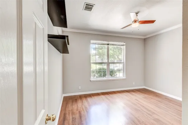 an empty room with wooden floor and windows
