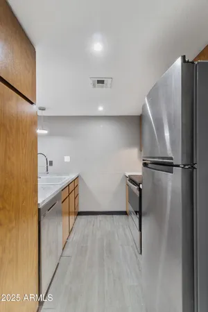 a kitchen with stainless steel appliances kitchen island granite countertop a refrigerator a stove and a sink with wooden floor