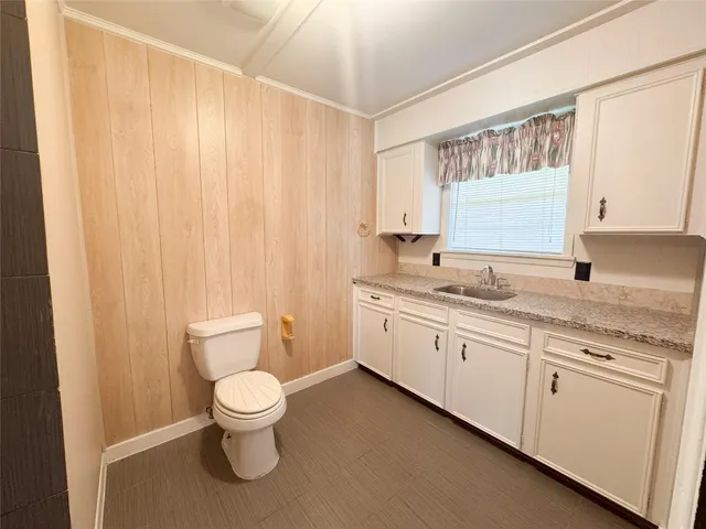 a bathroom with a granite countertop toilet a sink and a large mirror