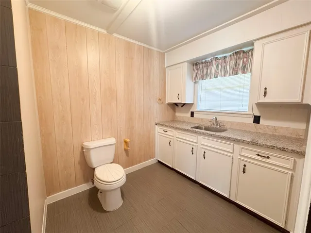 a bathroom with a granite countertop toilet a sink and a large mirror