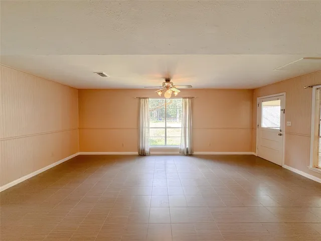 an empty room with windows and chandelier fan