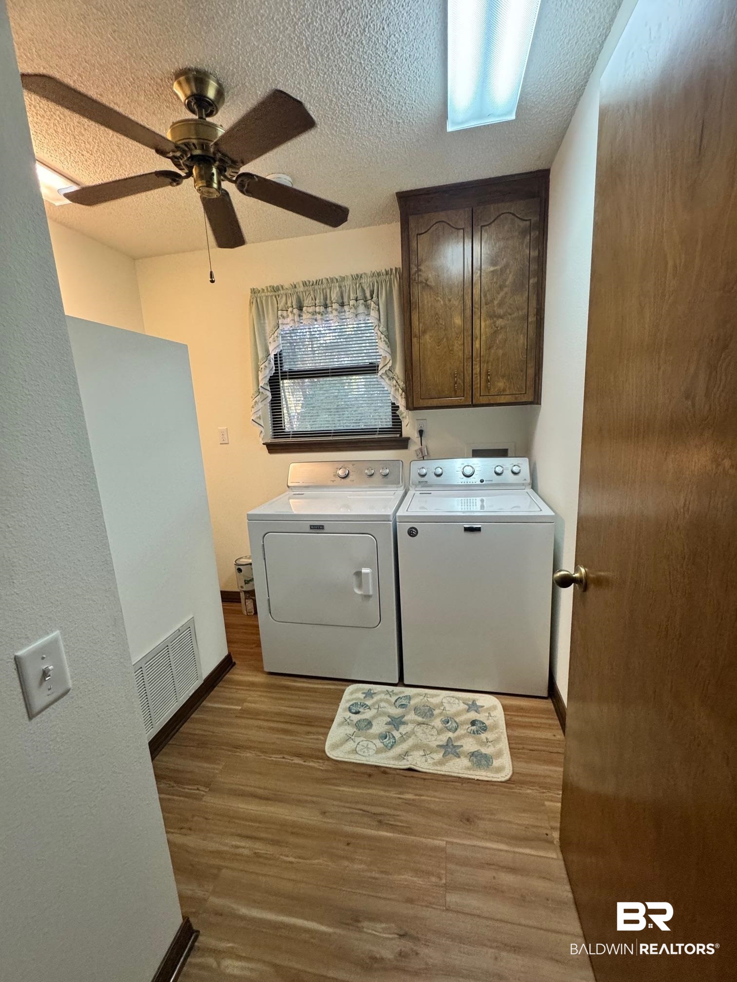 2682 Pine Ridge Drive Lillian, AL 36549 - Photo 16 of 37 Washroom featuring cabinets, light hardwood / wood-style flooring, ceiling fan, independent washer and dryer, and a textured ceiling