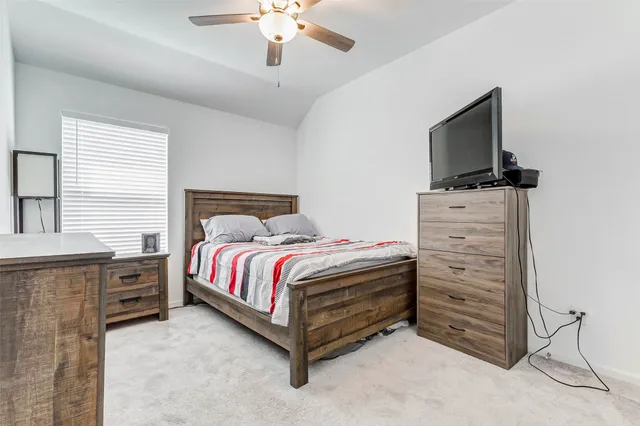 a bedroom with a bed and a flat tv screen on dresser