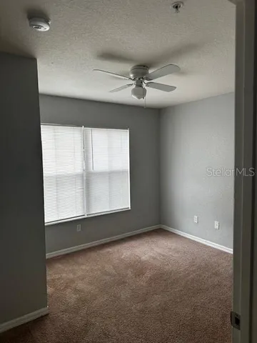 en empty room with windows and ceiling fan
