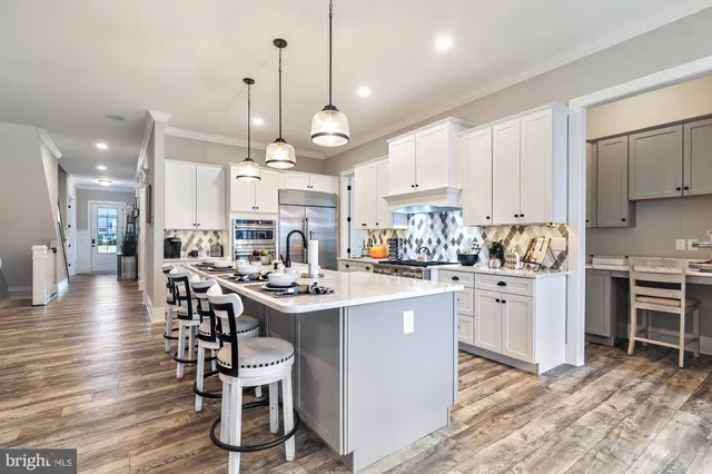a kitchen with kitchen island a dining table chairs sink and wooden floor