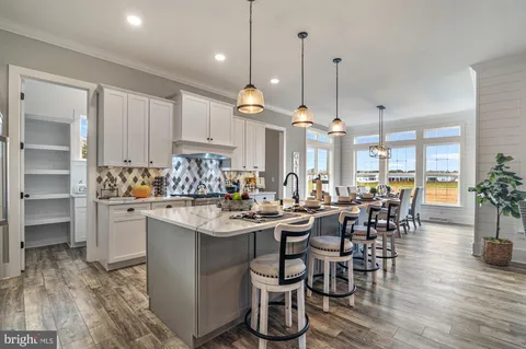 a view of a dining room and livingroom with furniture wooden floor kitchen chandelier
