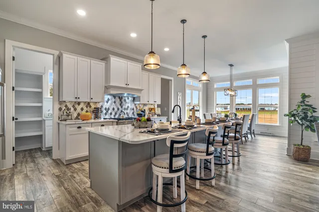 a view of a dining room and livingroom with furniture wooden floor kitchen chandelier
