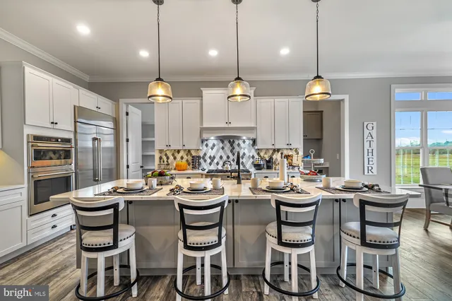 a room with stainless steel appliances kitchen island granite countertop a stove a sink a dining table and chairs