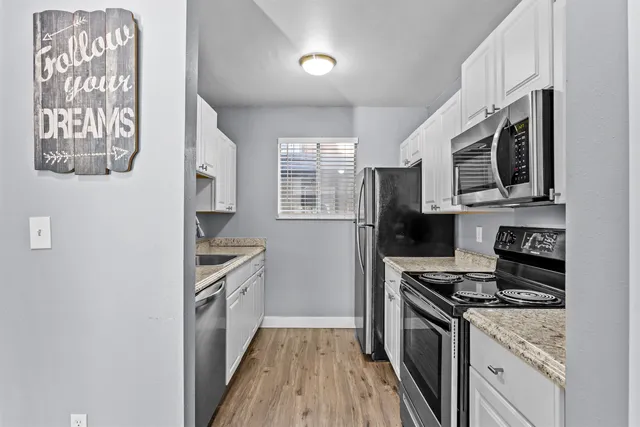 a kitchen with stainless steel appliances granite countertop a stove a sink and a refrigerator