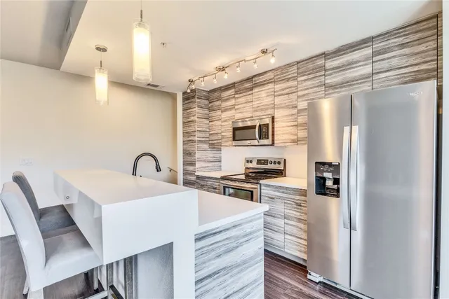 a kitchen with stainless steel appliances a stove a refrigerator a sink and white cabinets with wooden floor