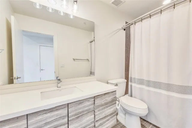 a bathroom with a sink a toilet a mirror a vanity and shower