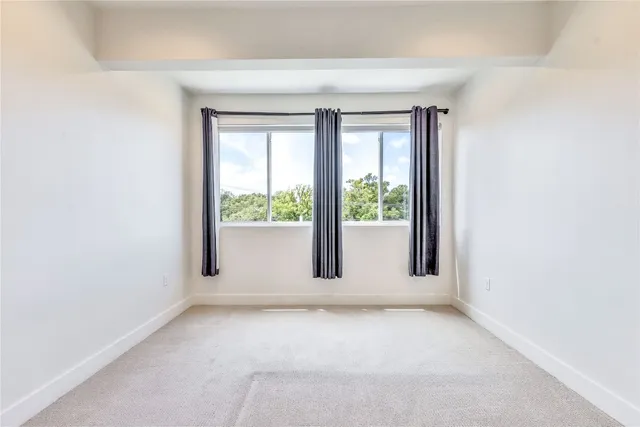 an empty room with ceiling fan and window