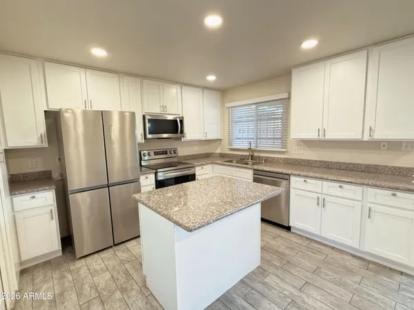 a kitchen with kitchen island granite countertop appliances cabinets and a sink