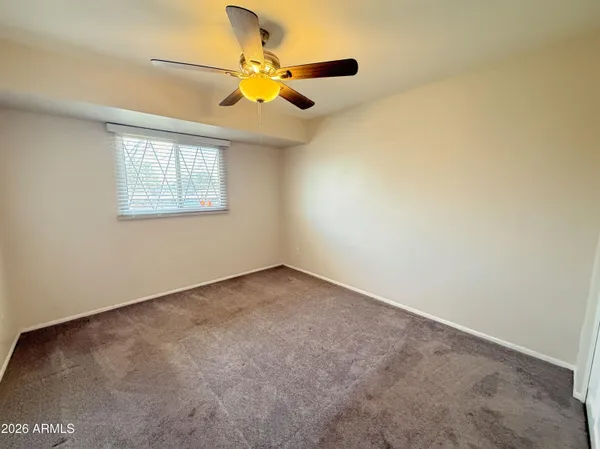 an empty room with a window and a fan