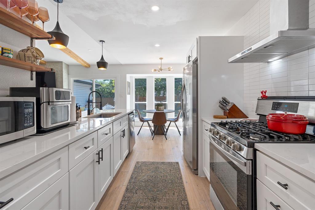 4902 Carsonhill Drive Austin, TX 78723 - Photo 9 of 19 Kitchen with stainless steel appliances, wall chimney exhaust hood, white cabinetry, light stone counters, and recessed lighting