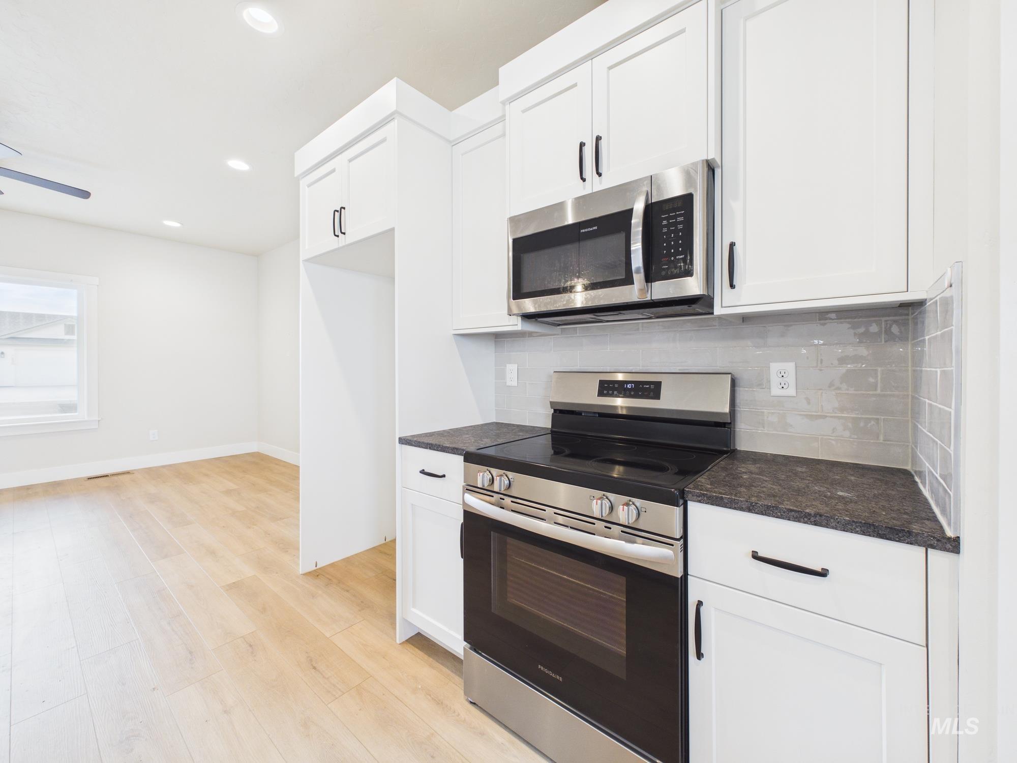1545 Trail Way Weiser, ID 83672 - Photo 12 of 50 Kitchen with stainless steel appliances, white cabinets, light wood finished floors, decorative backsplash, and recessed lighting