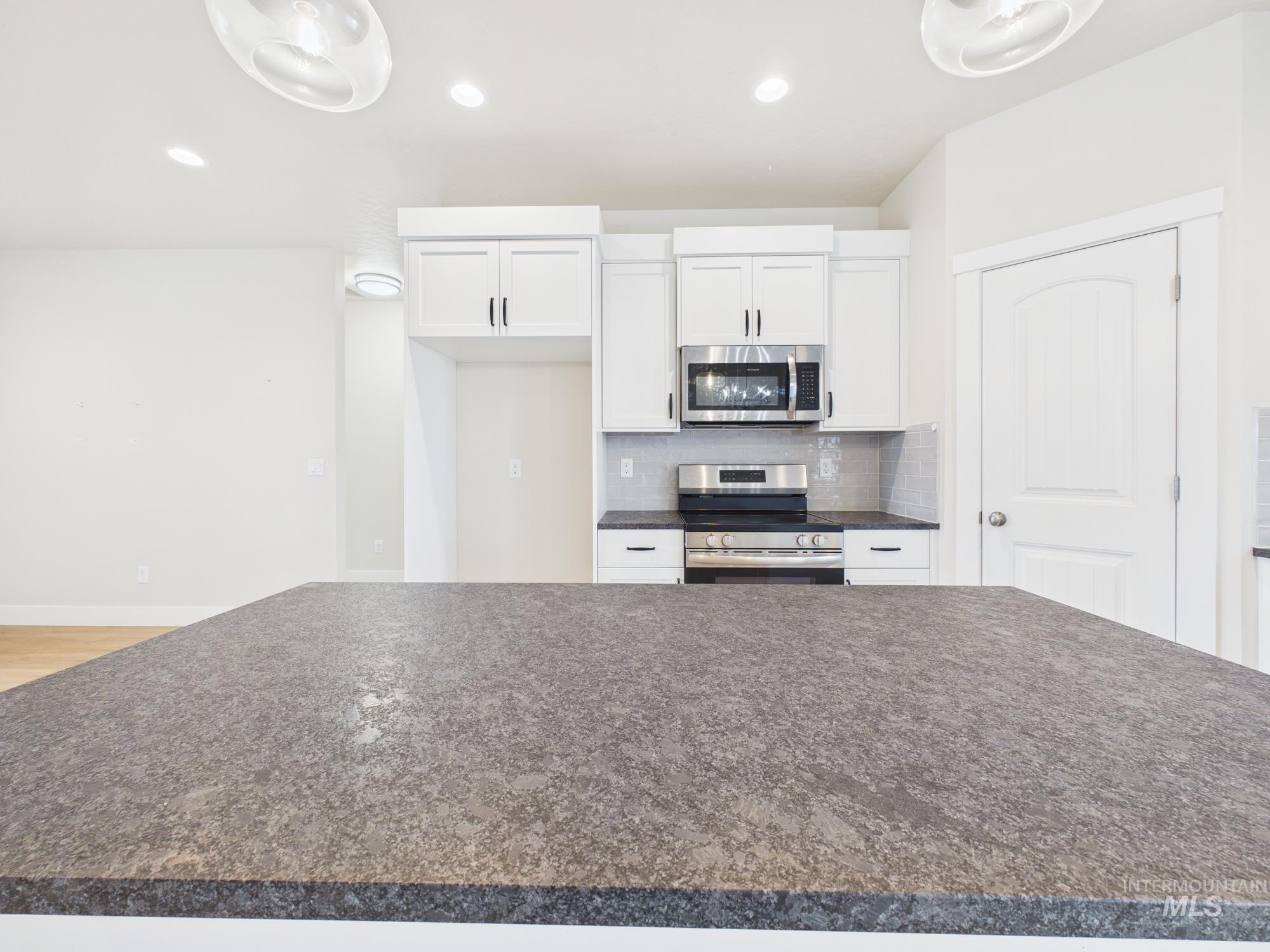 1545 Trail Way Weiser, ID 83672 - Photo 13 of 50 Kitchen with dark countertops, white cabinetry, tasteful backsplash, stainless steel appliances, and decorative light fixtures