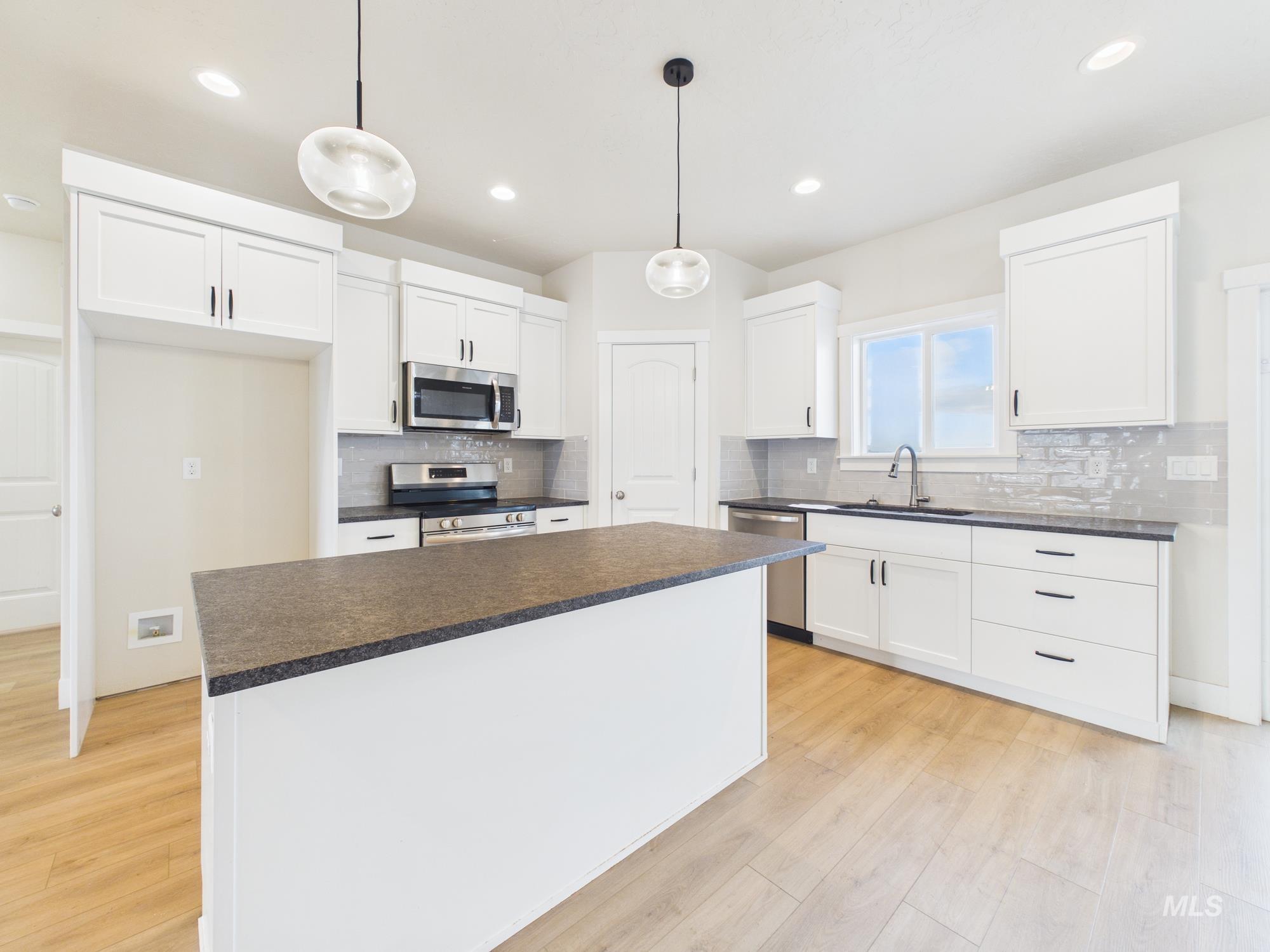 1545 Trail Way Weiser, ID 83672 - Photo 14 of 50 Kitchen with white cabinets, stainless steel appliances, decorative light fixtures, dark countertops, and light wood finished floors
