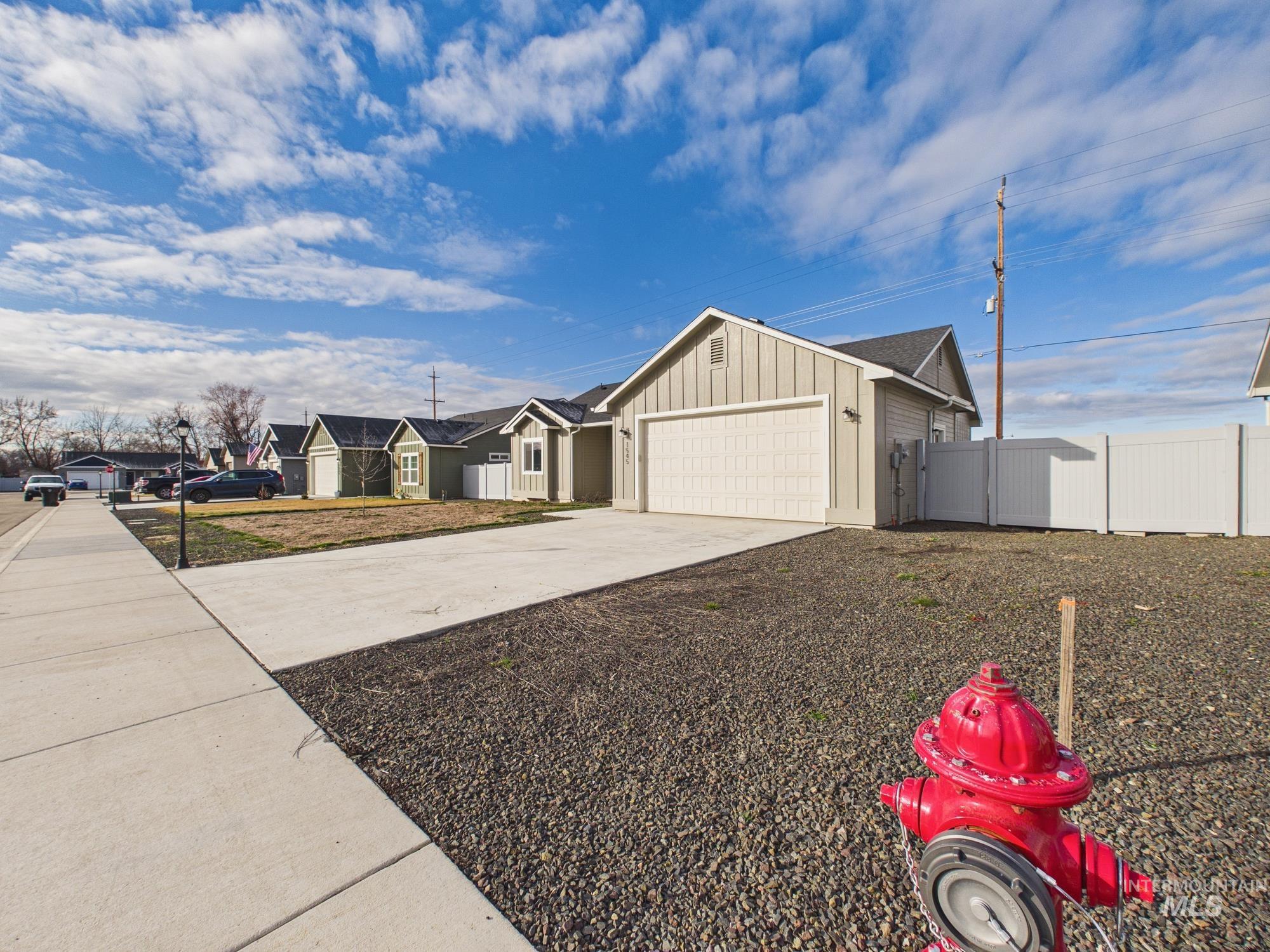 1545 Trail Way Weiser, ID 83672 - Photo 45 of 50 View of property exterior featuring a residential view, a garage, concrete driveway, and board and batten siding