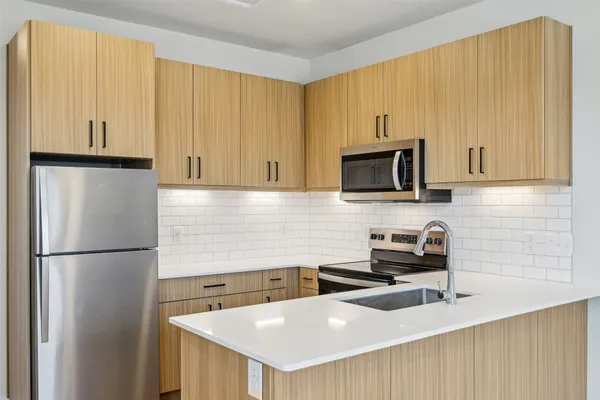 a kitchen with stainless steel appliances a refrigerator a sink a stove cabinets and a refrigerator