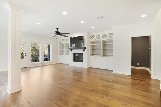an empty room with wooden floor and kitchen view
