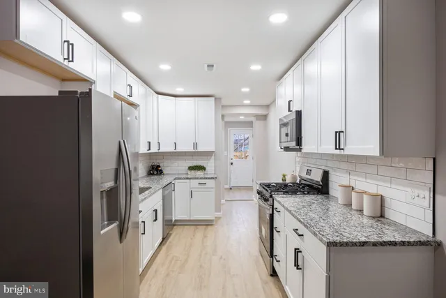 a large kitchen with stainless steel appliances granite countertop a sink stove and refrigerator