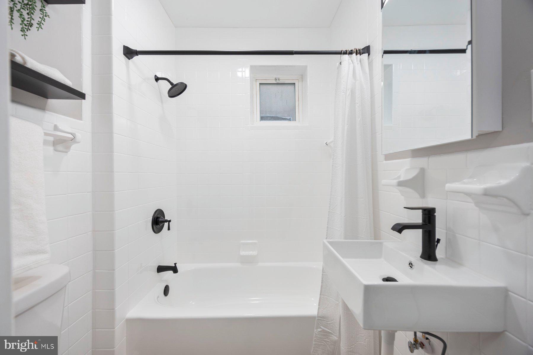 3611 Chestnut Avenue Baltimore, MD 21211 - Photo 26 of 38 a bathroom with a white sink a shower and a bathtub