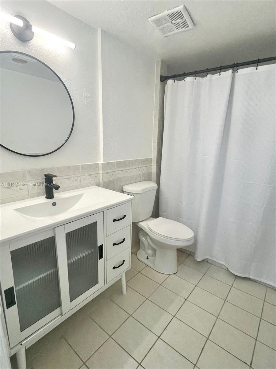 800 Northeast 199th Street, Unit 106D Miami, FL 33179 - Photo 11 of 20 a bathroom with a sink mirror vanity and toilet