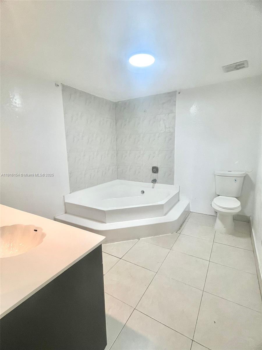 800 Northeast 199th Street, Unit 106D Miami, FL 33179 - Photo 17 of 20 a bathroom with a sink a toilet and a mirror