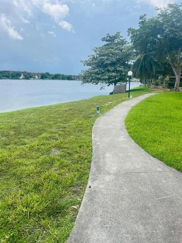 a view of a lake with a big yard and large trees