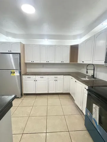 a large kitchen with stainless steel appliances granite countertop a stove a sink and a refrigerator