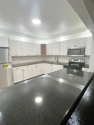 a kitchen with stainless steel appliances a sink a stove a microwave a sink and cabinets