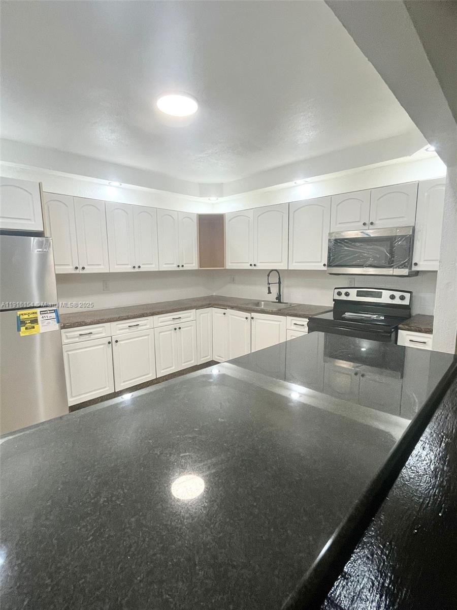 800 Northeast 199th Street, Unit 106D Miami, FL 33179 - Photo 6 of 20 a kitchen with stainless steel appliances a sink a stove a microwave a sink and cabinets
