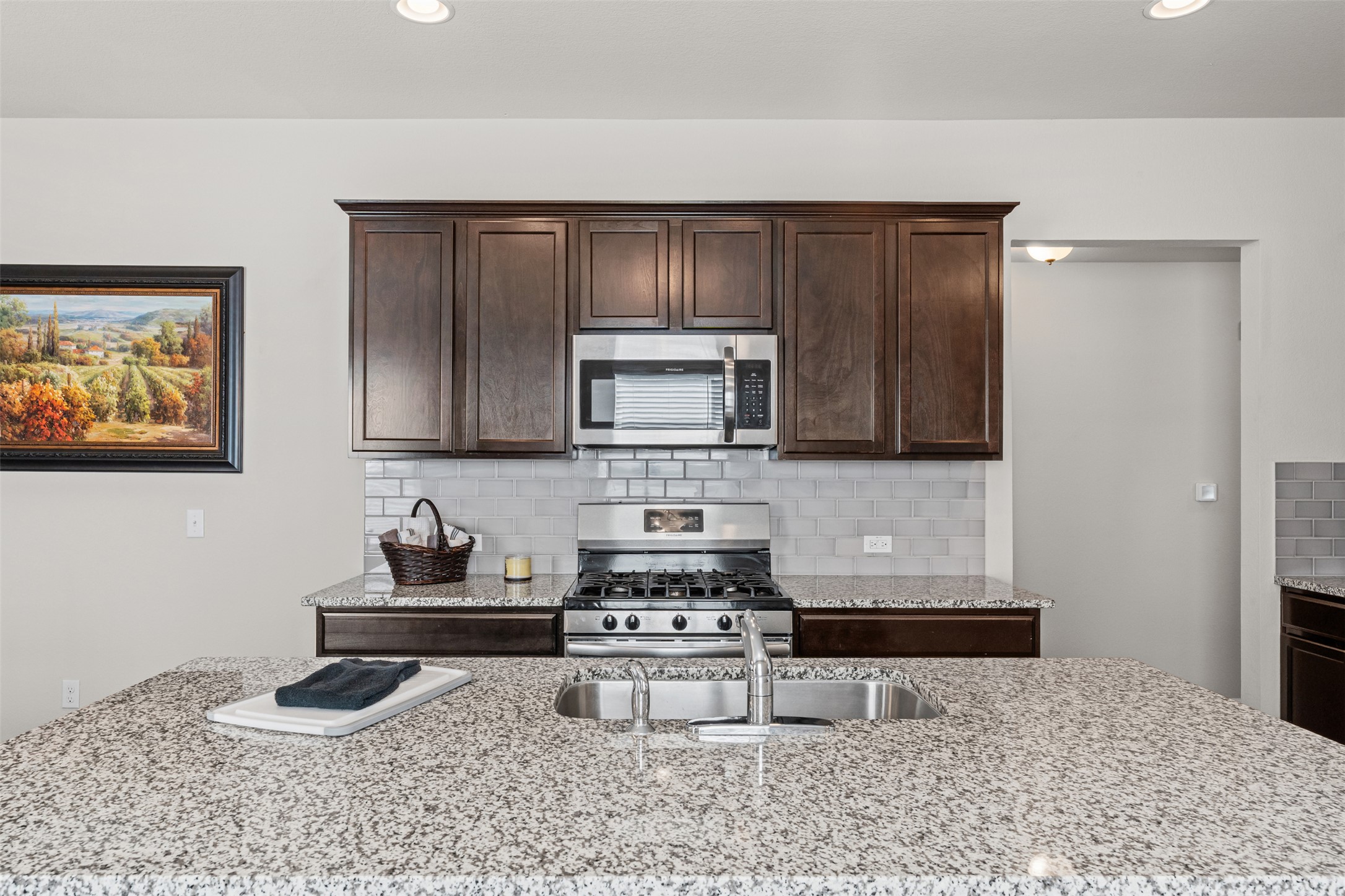 132 Dunlin Lane Leander, TX 78641 - Photo 5 of 34 Kitchen featuring backsplash, dark brown cabinets, appliances with stainless steel finishes, light stone countertops, and recessed lighting