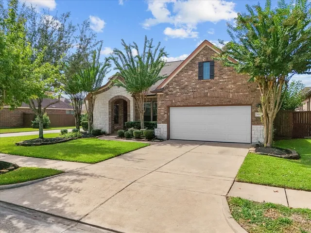 a front view of a house with a garden and trees