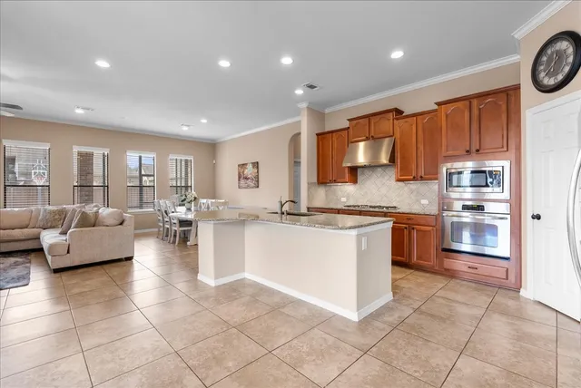 a large kitchen with stainless steel appliances a stove a sink and a refrigerator