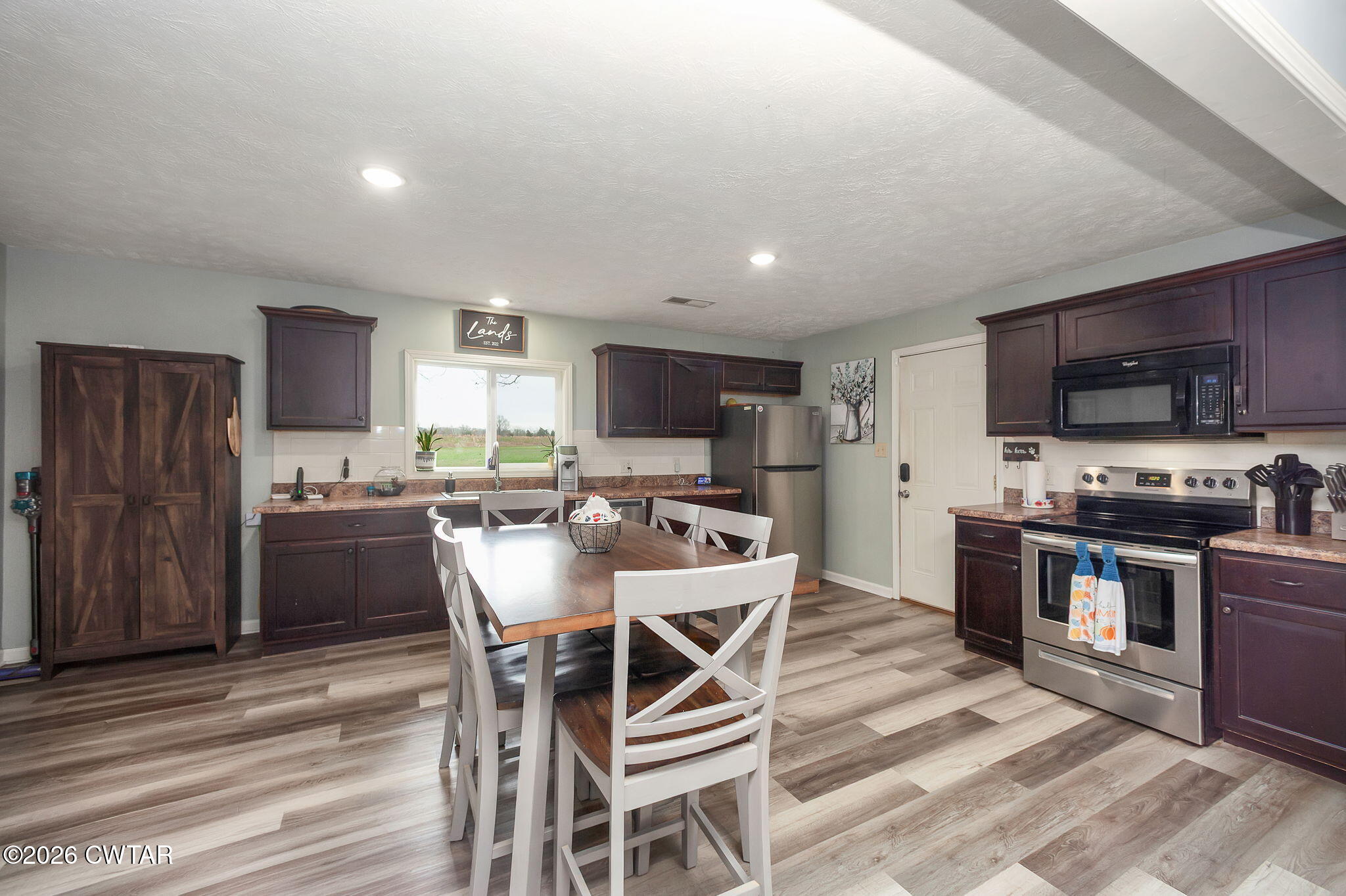 919 Bratt Thomas Road Brownsville, TN 38012 - Photo 11 of 29 a kitchen with stainless steel appliances granite countertop a stove top oven a sink dishwasher a dining table and chairs with wooden floor