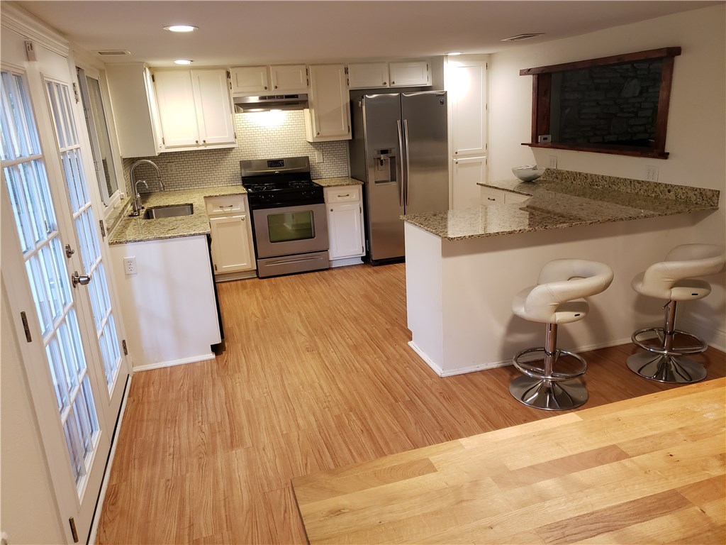 7003 Bill Hughes Road Austin, TX 78745 - Photo 1 of 1 a kitchen with stainless steel appliances granite countertop a refrigerator a stove a sink and a dining table with wooden floor