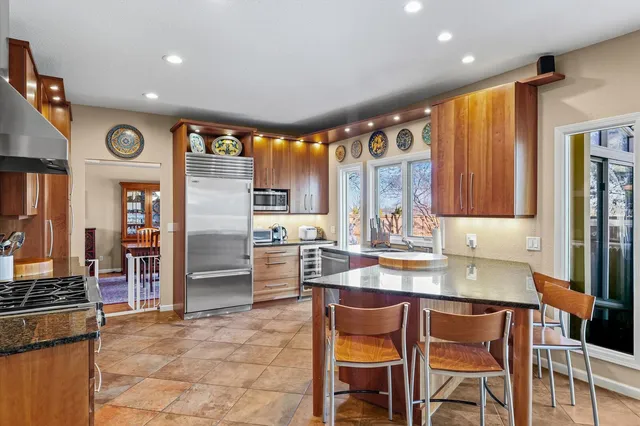 a kitchen with stainless steel appliances granite countertop a stove top oven a refrigerator and a sink