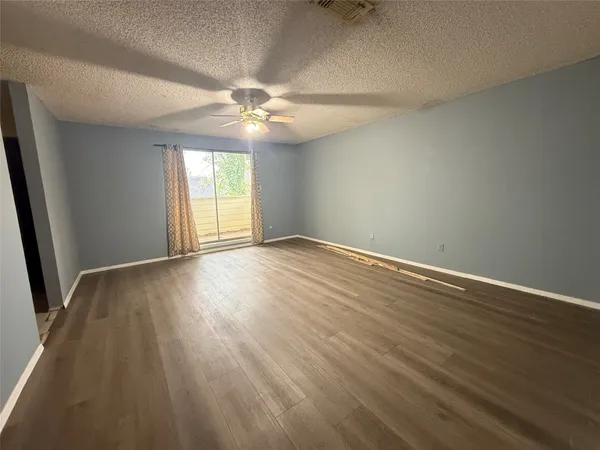 an empty room with wooden floor fan and windows