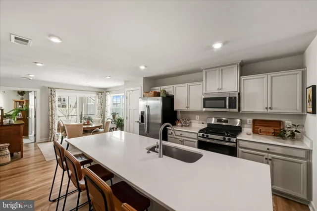 a kitchen with stainless steel appliances a stove a sink a microwave a refrigerator and cabinets