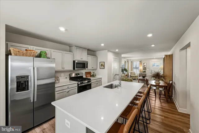 a kitchen with stainless steel appliances a refrigerator a stove a sink a dining table and chairs